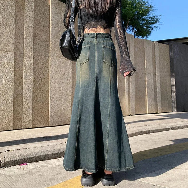 Person wearing wide-leg jeans and black shoes on a sidewalk.