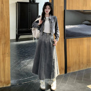 Woman in a denim outfit standing in a room with wooden walls and a bed.