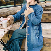 Person wearing a blue denim coat with fur trim sitting outdoors.