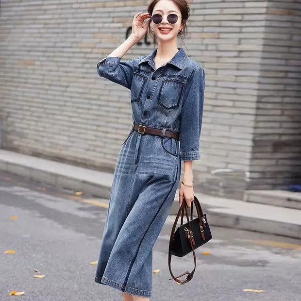 Woman wearing a denim jumpsuit with sunglasses and a handbag on a street.