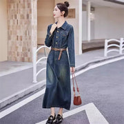 Woman in a denim dress holding a brown handbag on a street.
