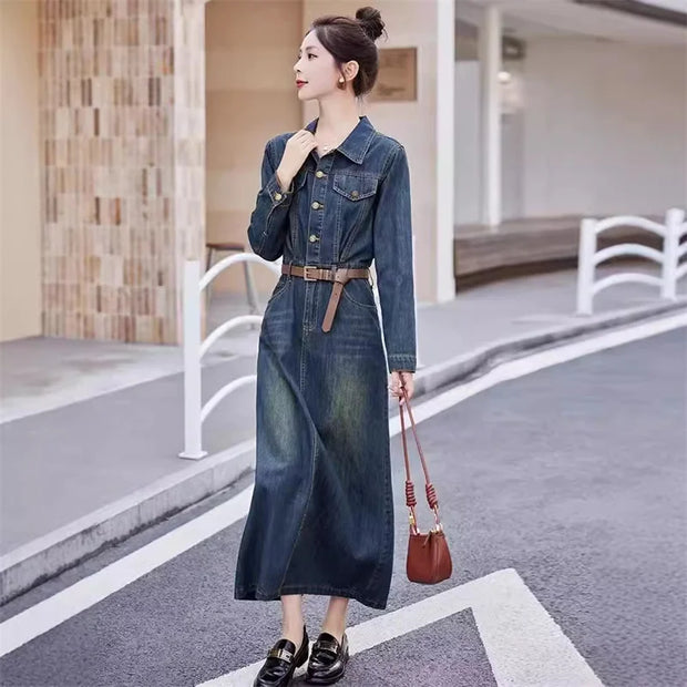 Woman in a denim dress holding a brown handbag on a street.