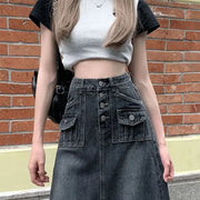 Person wearing a gray crop top and black denim skirt against a brick wall.