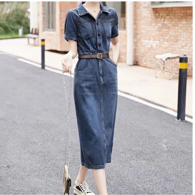 Person wearing a denim dress on a street with a brick building in the background