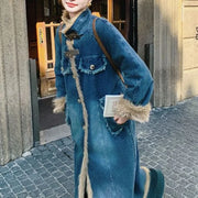 Person wearing a long blue denim coat with fur trim on a street.