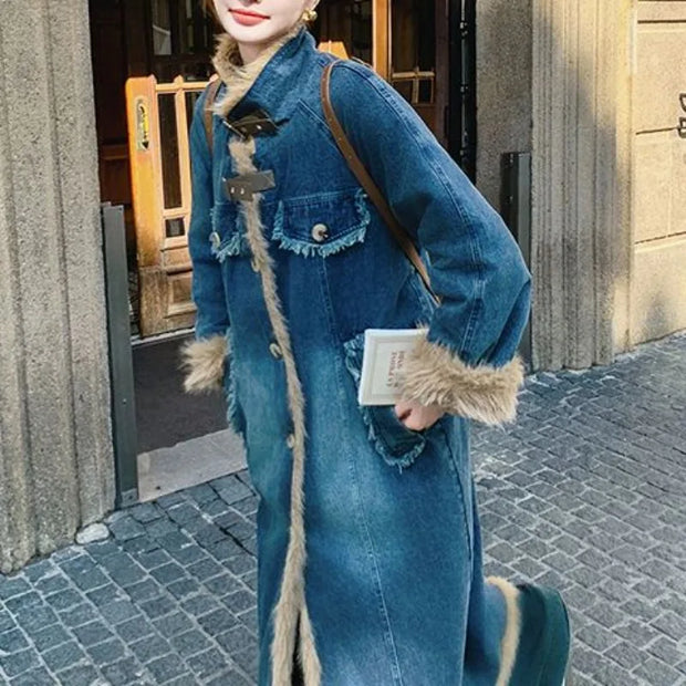 Person wearing a long blue denim coat with fur trim on a street.