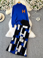 Blue sweater with orange letter 'H' and black and white patterned pants on a textured surface with flowers.