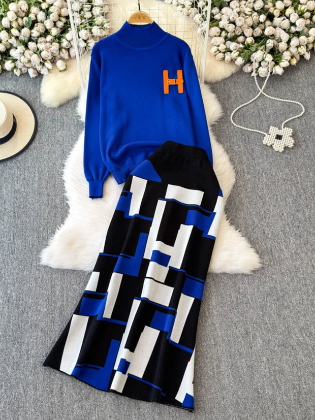 Blue sweater with orange letter 'H' and black and white patterned pants on a textured surface with flowers.