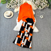 Orange top and black and white patterned pants on a gray surface with decorative elements.