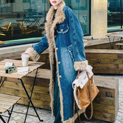 Person wearing a long denim coat with fur trim sitting at an outdoor cafe.