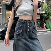 Person wearing a gray crop top and denim skirt on a street.