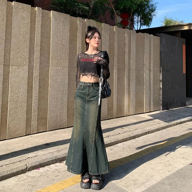 Woman in black cropped top and green wide-leg pants standing on a sidewalk.