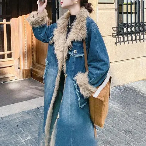 Person wearing a long denim coat with fur trim on a street.