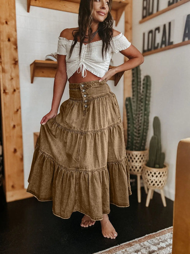 Woman wearing a white top and brown skirt in a room with wooden walls and cacti.