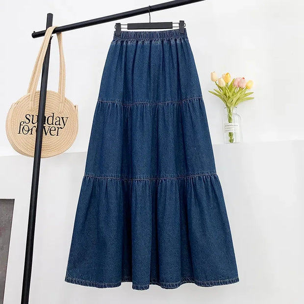 Blue denim skirt hanging on a rack with a 'Sunday Forever' bag and flowers in the background.