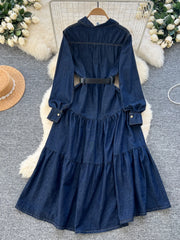 Blue denim dress on a hanger with decorative elements on a textured surface