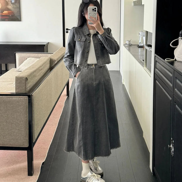 Person taking a mirror selfie in a modern kitchen wearing a denim jacket and skirt.