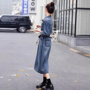 Woman wearing a long denim dress on a city street.