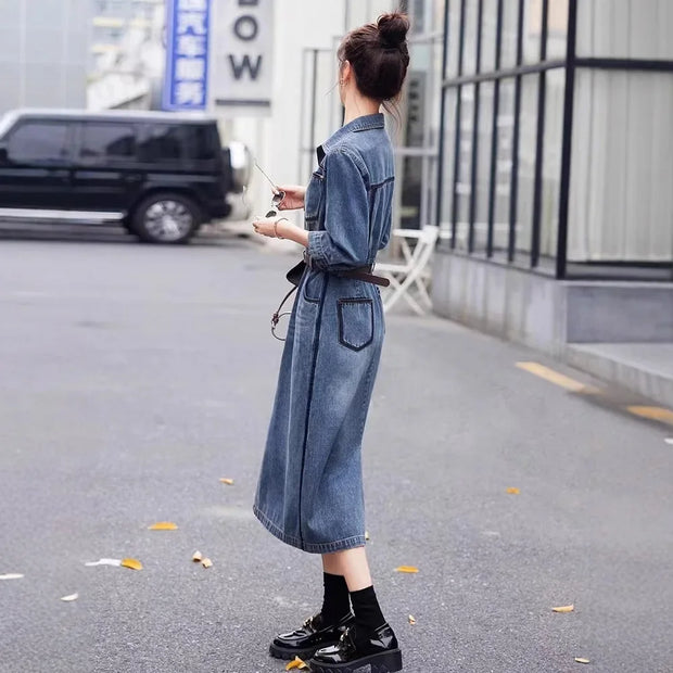 Woman wearing a long denim dress on a city street.